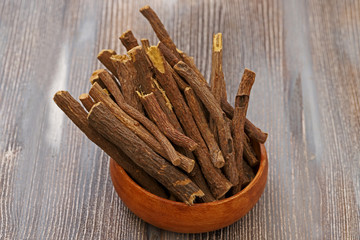 of a heap pile of Liquorice licorice roots sticks on a wooden board, its sweet fresh flavor can be extracted similar to star anise or fennel, used to flavor tobacco or to make rolled up candy