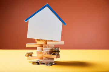 Real property investment or development of housing industry. House mockup and coins on wooden...