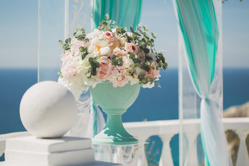 Wedding arch for the ceremony and a vase with wedding flowers, against the background of the sea