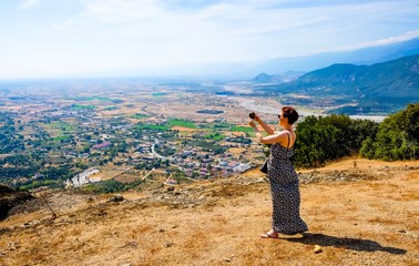 Woman at Meteora, Greece, making picture to mobile