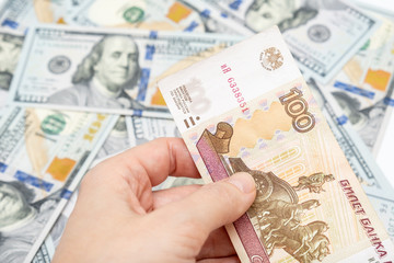 A hand holding one hundred ruble and american dollar banknotes on background, ruble devaluation and usd-rub exchange rate concept, hundred rubles for one dollar