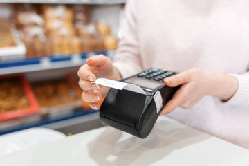 A woman holds a payment terminal while holding a receipt for completing a purchase. Hands close up. The concept of NFC, business and banking transactions