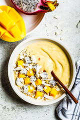 Mango smoothie bowl with granola and dragon fruit in white bowl, top view. Healthy breakfast concept.