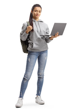 Female student with backpack holding a laptop computer and smiling at the camera