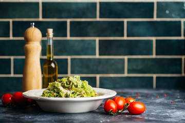 Italian pasta food background. Vegan italian pasta with spinach (Spinach Fettuccine Alfredo Pasta) on a white plate. Old kitchen background. Copy space