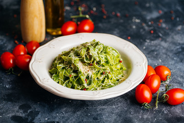 Italian pasta food background. Vegan italian pasta with spinach (Spinach Fettuccine Alfredo Pasta) on a white plate. Old kitchen background. Copy space