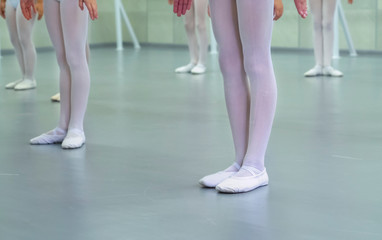 closeup legs of little ballerinas group in white shoes practicing in ballet school slow motion