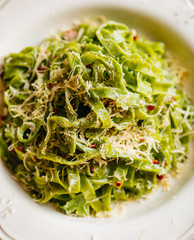 Italian pasta food background. Vegan italian pasta with spinach (Spinach Fettuccine Alfredo Pasta) on a white plate. Old kitchen background. Copy space
