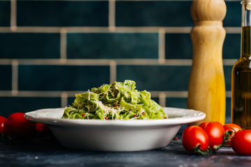 Italian pasta food background. Vegan italian pasta with spinach (Spinach Fettuccine Alfredo Pasta) on a white plate. Old kitchen background. Copy space