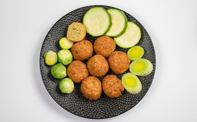 Cooking of healthy vegetarian food, tasty check pea falafels and frehs green vegetables