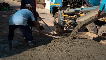Asian construction workers group with cement mixer truck are pouring concrete on the floor in...