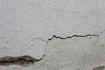 Obraz premium Old foundation and plaster wall with cracks. Building requiring repair closeup.
