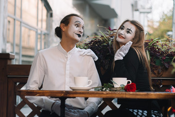 Two happy mime on a date drink coffee in the cafe. Romantic date