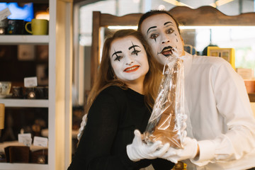 Fototapeta premium Happy man mime giving a chocolate eiffel tower to his girlfriend. Two happy mimes on a date in the cafe