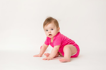 healthy baby girl in a pink bodysuit sits on a white background. space for text