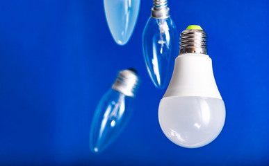Different bulbs fall down. Electric lighting. Blurred background. Power saving LED lamps in comparison with incandescent lamps. Environmental friendliness.