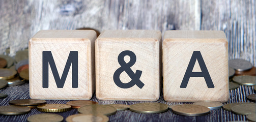 Mergers and acquisitions, M&A concept. Text on wooden cubes and cash coins