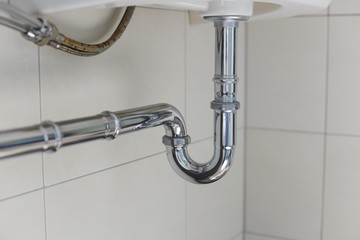 metal sink siphon and drain in white bathroom