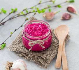 Russian appetizer horseradish with beetroot in a jar in rustic style on a light background