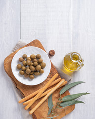 Fototapeta na wymiar ripe natural eco friendly olives with olive oil in a bottle and grissini on a white wooden background