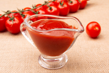 Ketchup and ripe cherry tomatoes, on burlap