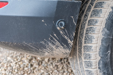 Verschmutzte Stoßstange eines Autos ohne Schmutzfänger hinter dem Autoreifen