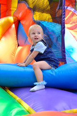 Joyful girl jumps on inflatable attractions