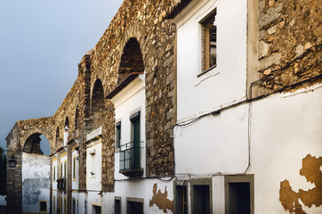 Houses in Evora (Alentejo, Portugal) along the ancient Agua da Prata aqueduct. Buildings were built during centuries directly between the arches of the aqueduct