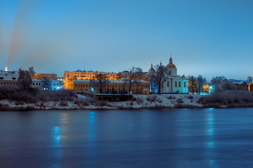 View across the river of the night city of Polotsk with the Epiphany Cathedral and reflection of lanterns in the river