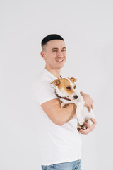 Young man with his dog at studio. Young owner hugs his pet. young and beautiful man holding his dog in his arms with love and playing with him, against a white background