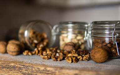 Walnut scattered on the white vintage table from a jar whith a whole walnuts. Walnut is a healthy vegetarian protein nutritious food. Walnut kernels and whole walnuts on rustic old wood.