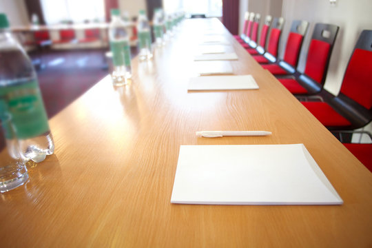 Bottle of water and handouts on the desk. Conference room in a hotel for business training.  Interior of empty modern meetingroom. Rows of chairs and desks. .