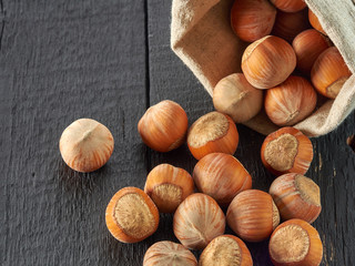 Hazelnuts lie in a plate on a black wooden background