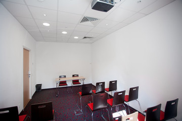 Interior of empty modern meetingroom. Conference room in a hotel for business training. Rows of chairs and desks. Boardroom with presentation screen and projector...
