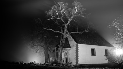 Small old chapel on hill surrounded by fog in the mythical dark night in the Black Forest