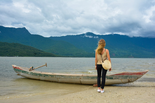 Young, blonde girl and a wooden fishing boat in Lap An Lagoon. Tranquil scene in Hue, Vietnam