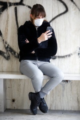 donna con mascherina e telefono cellulare