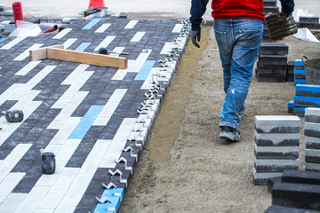 Construction work on pavement. Installation of concrete paver blocks on the sidewalk. The worker pavers pavement bricks on a pre-prepared surface of concrete mortar.