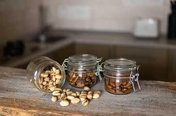 Pistachios scattered on the white vintage table from a jar and with other nuts on background. Pistachio is a healthy vegetarian protein nutritious food. Pistachios on rustic old wood.