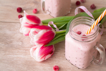 Refreshing raspberry smoothie made with milk and fresh raspberries. Tulip flowers and tape mesure, spring concep