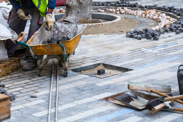 Construction work on pavement. Installation of concrete paver blocks on the sidewalk. The worker...