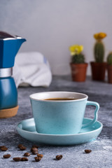 Obraz na płótnie Canvas Black coffee in a cup, geyser coffee maker and coffee beans on a board, blurred bokeh background.