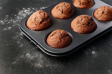 homemade muffins, in a baking dish on a dark surface