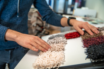 the man chooses the color of the new carpet according to the pattern book in the flooring shop