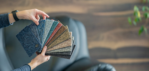The man selects a new cover for the sofa from the color card sampler