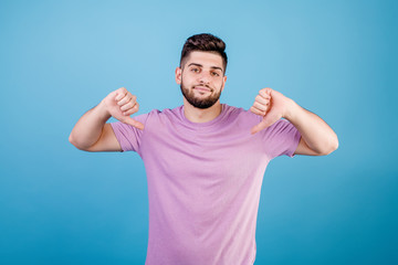 Fototapeta premium unhappy disappointed man showing thumbs down isolated on blue background