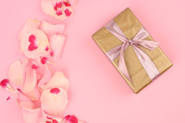 Flat lay composition with beautiful flowers and a gift box on a pink background. Space for text