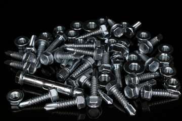 Pile of fasteners.  Bolts, nuts, screws, anchor bolts on a black background.  Assorted Fixing...