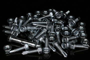 Pile of fasteners.  Bolts, nuts, screws, anchor bolts on a black background.  Assorted Fixing material.  © AndreySoyka