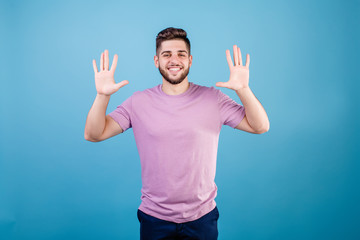 Fototapeta premium smiling man showing ten fingers isolated on blue background
